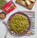 Pesto pasta in a bowl with a Dorot basil pack, nuts, and cheese on a board.