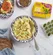 Bowl of creamy egg salad with dill, bread, eggs, and Dorot Dill on a marble counter.
