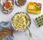 Bowl of egg salad with bread, eggs, and Dorot Gardens dill on a marble surface.