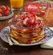 Pancakes topped with strawberries and powdered sugar.