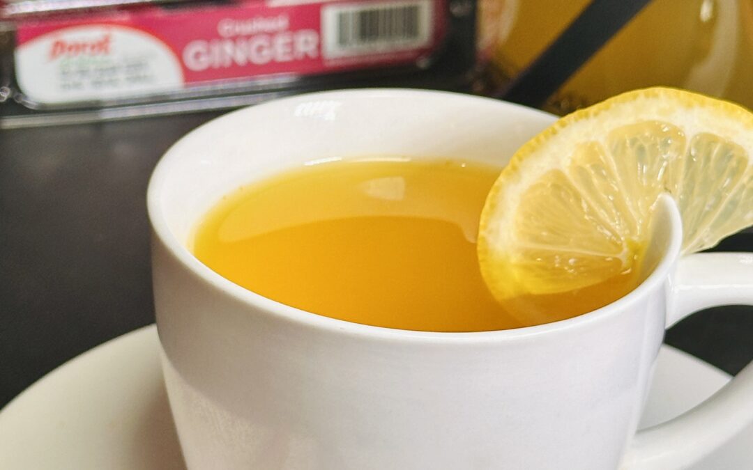 white coffee cup with tumeric ginger tea, topped with an orange slice